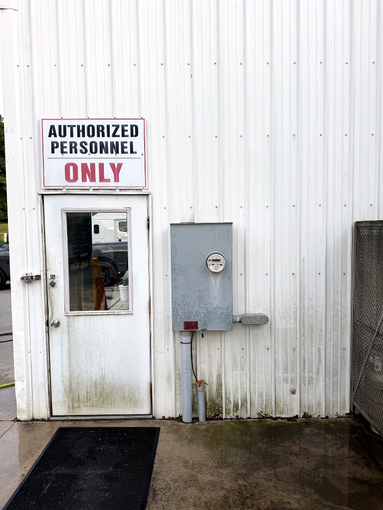 Building entrance before pressure washing — green algae and grime on lower walls and door